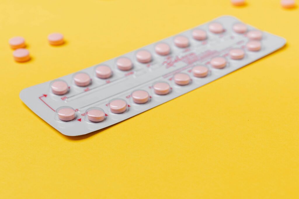 A blister pack of pink pills placed on a vibrant yellow background, symbolizing Long QT Syndrome Birth Control Risks for Women